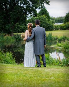 Bride and groom standing together looking out at a lake, candid documentary wedding photography by Leon Britton