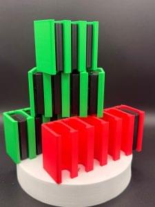Stack of 3D-printed Canon LP-E6 battery holders in green and red, made by Home Forge Studio
